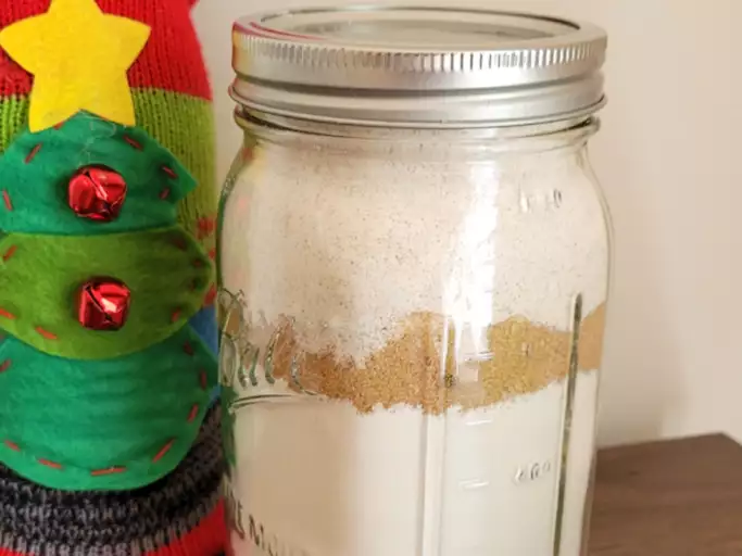A mason jar filled with the dry ingredients for a gingerbread cookie. 